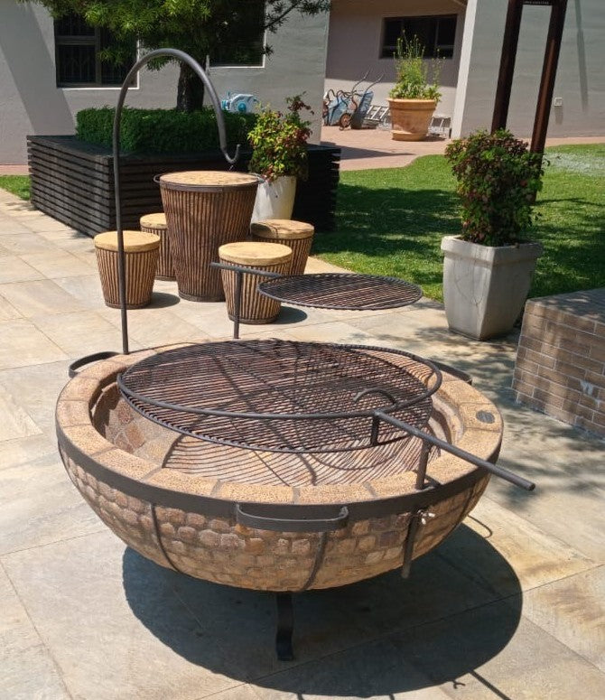 Outdoor patio with fire pit, stools, and potted plants on a sunny day.