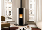 Modern freestanding stove in a living room with large windows.