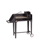 A black trolley braai grill with a stainless steel grid, integrated ash pan, and poker potjie hook, set on a frame with wheels and a work surface.