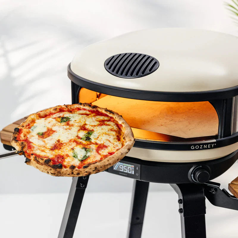 Gozney pizza oven with a freshly baked pizza on a white background