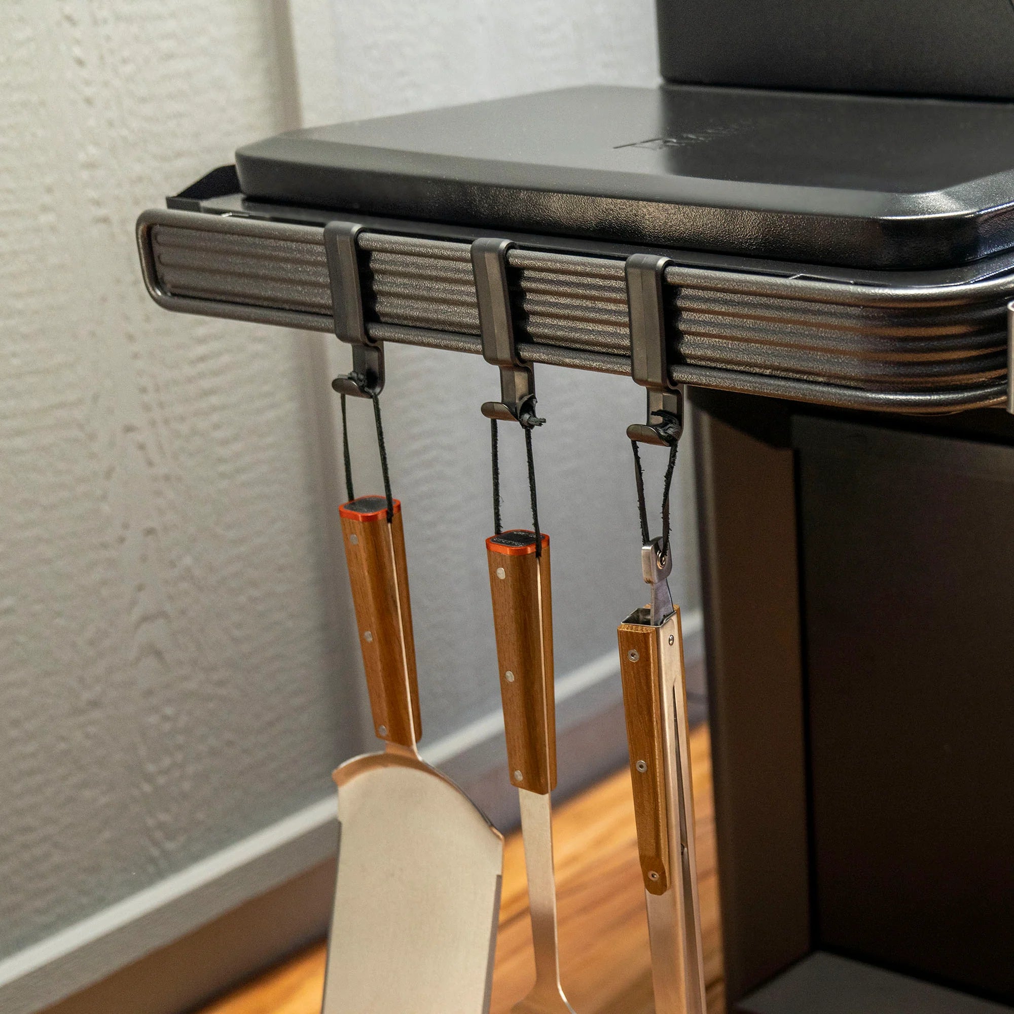 Wall-mounted tool holder with spatulas hanging on a gray wall.