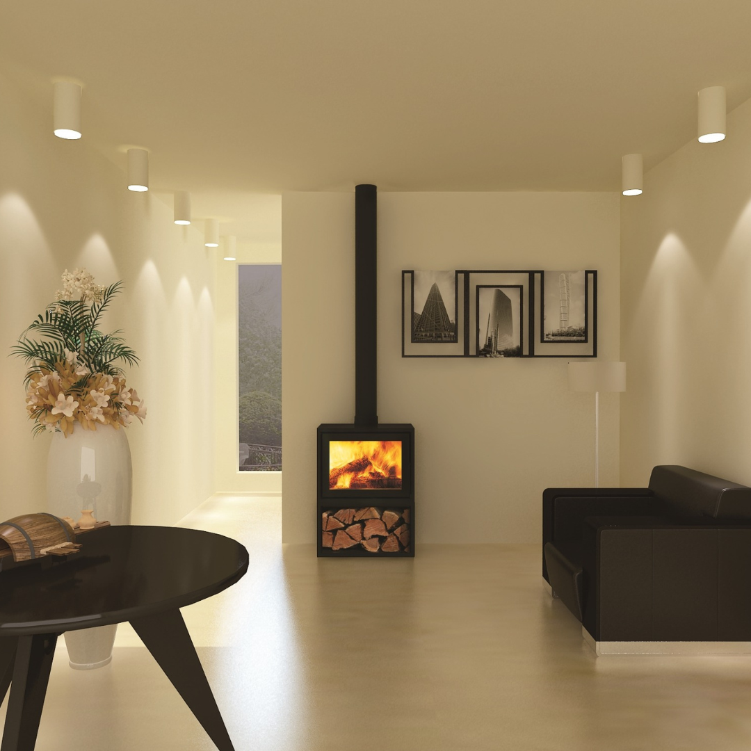 A modern, freestanding wood stove with a black chimney, situated in a well-lit living room setting, featuring a log holder and visible flames.