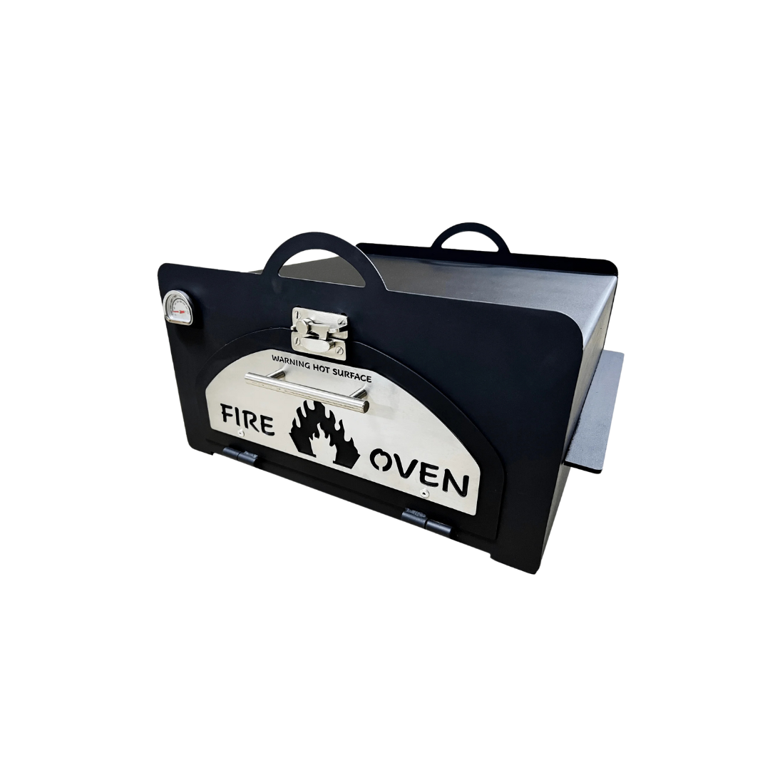 A black pizza oven insert with a white label that says 'FIRE OVEN' and a flame graphic. It has a handle on the top and a spatula resting on the side.