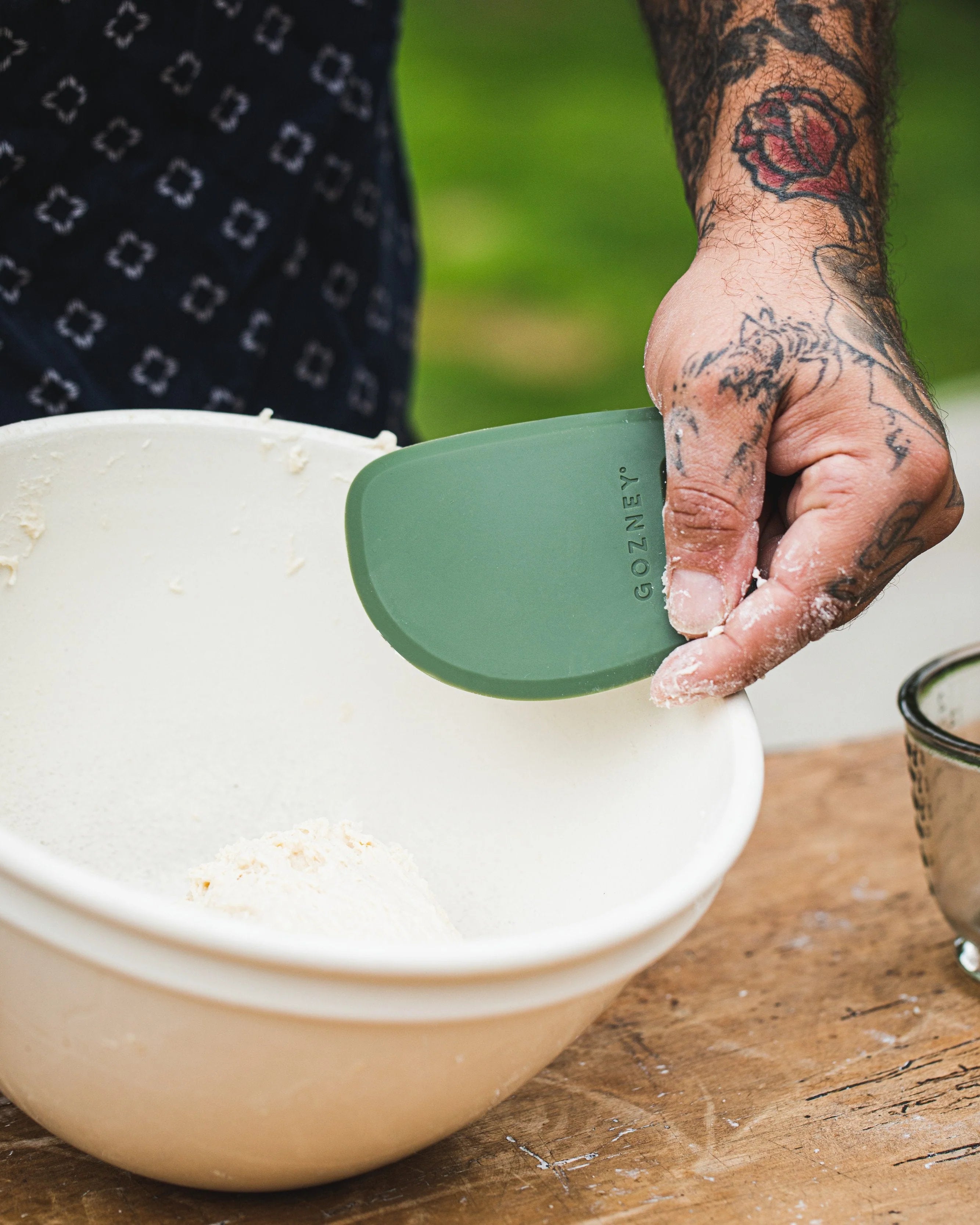 Person using a white and green kitchen tool on a wooden surface with a blurred background