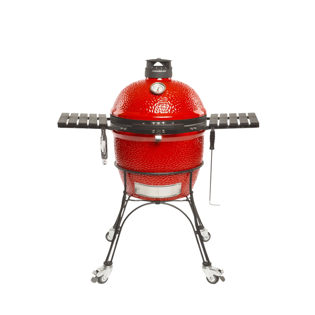 A red ceramic Kamado Joe Classic II charcoal grill with a steel wire cart and locking wheels, featuring side shelves and a built-in thermometer.