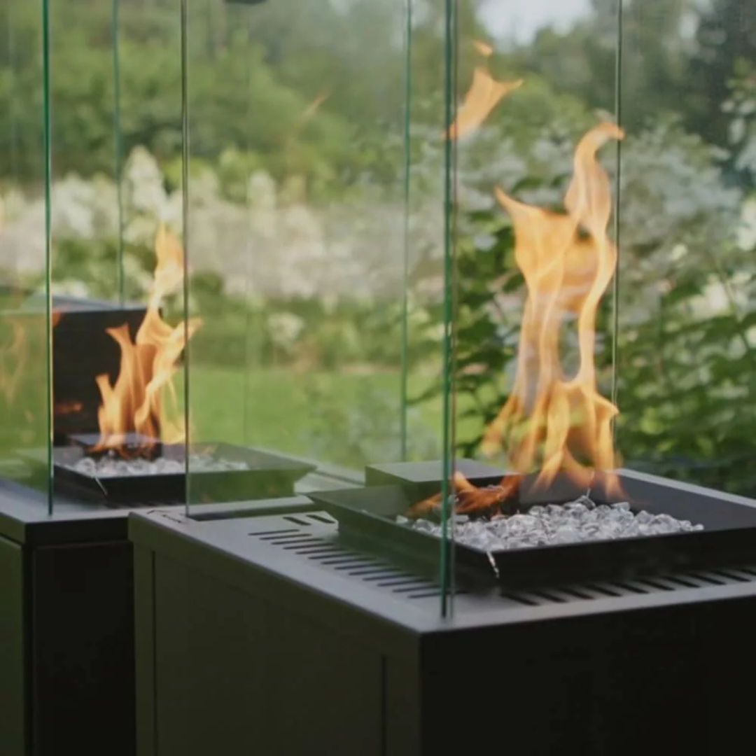 Kratki Patio M outdoor gas heater in garden setting with glass enclosure.