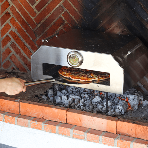 Wood fired pizza oven shown outdoors with food, lifestyle image for backyard dining