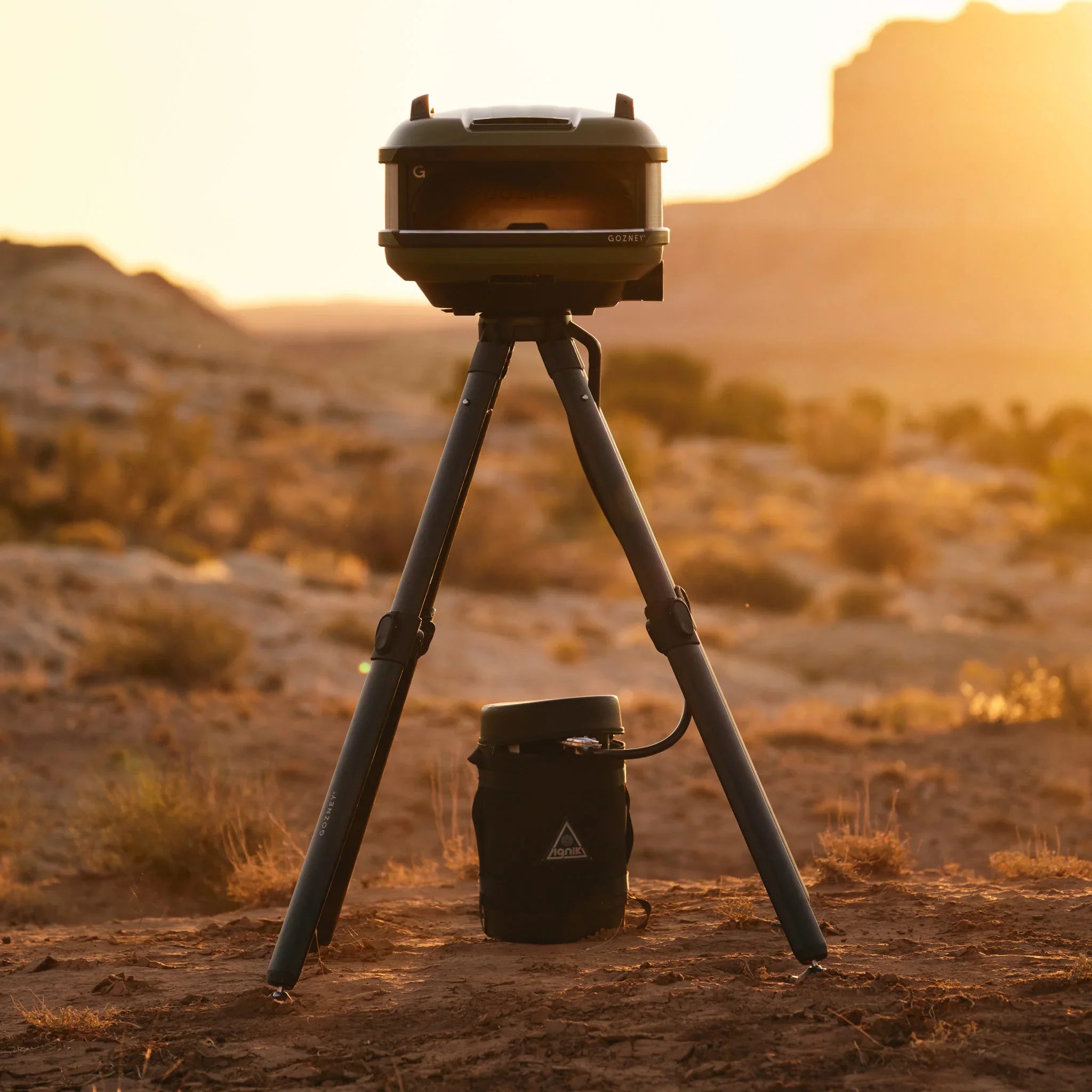 Tripod with a camera on a desert landscape during sunset