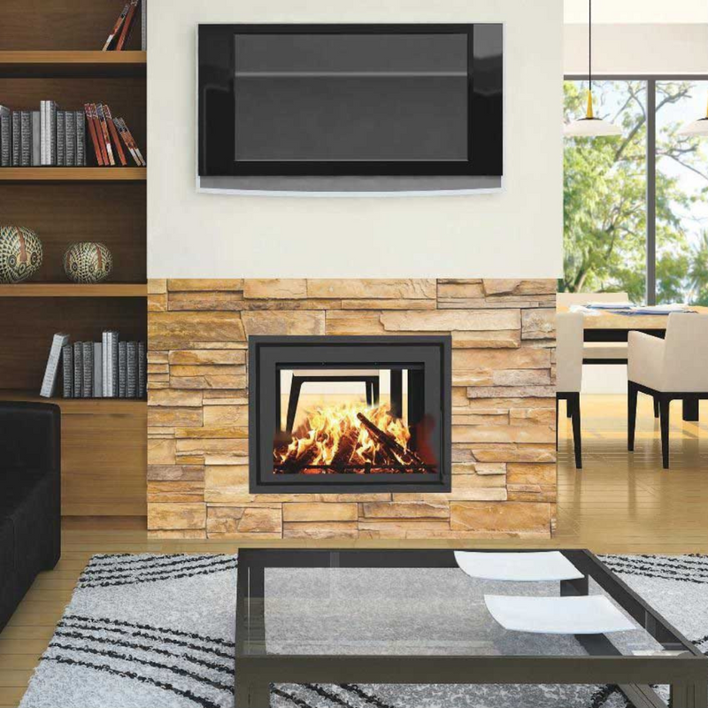 A modern fireplace with a double-sided glass insert, featuring a wood fire, is set into a stone wall in a living room.