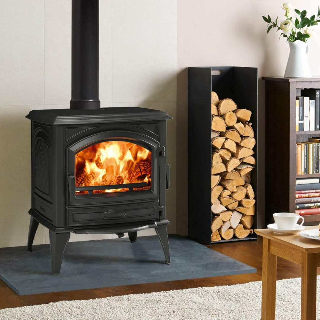 A black freestanding wood-burning fireplace with a visible fire through the glass door and wood pellets