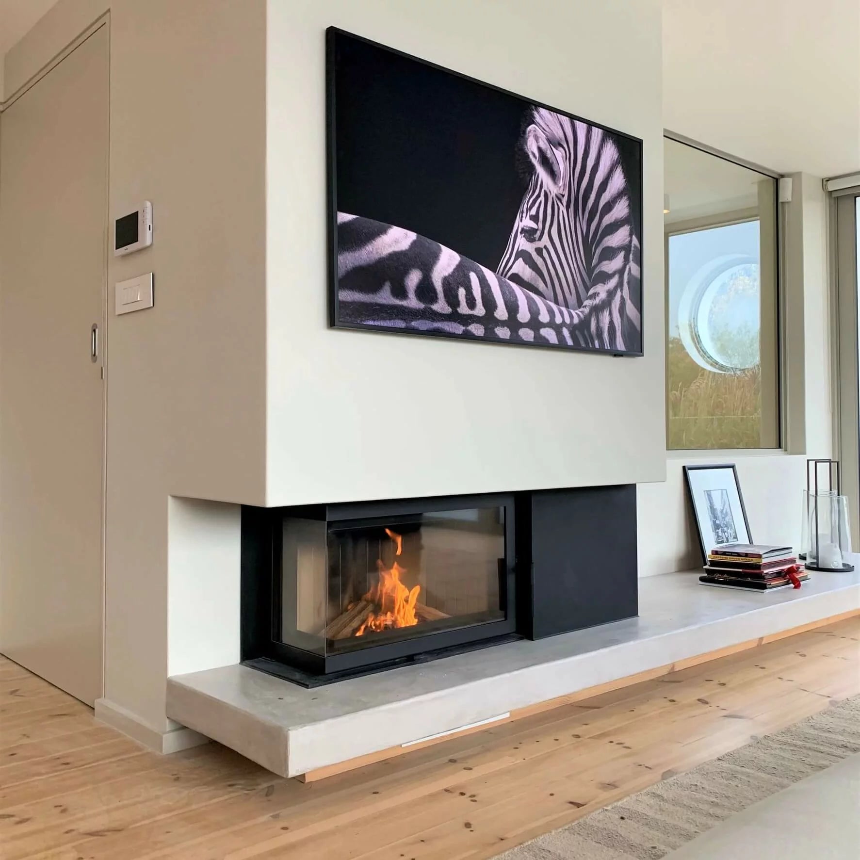 Modern living room with a fireplace and mounted TV displaying a zebra pattern.