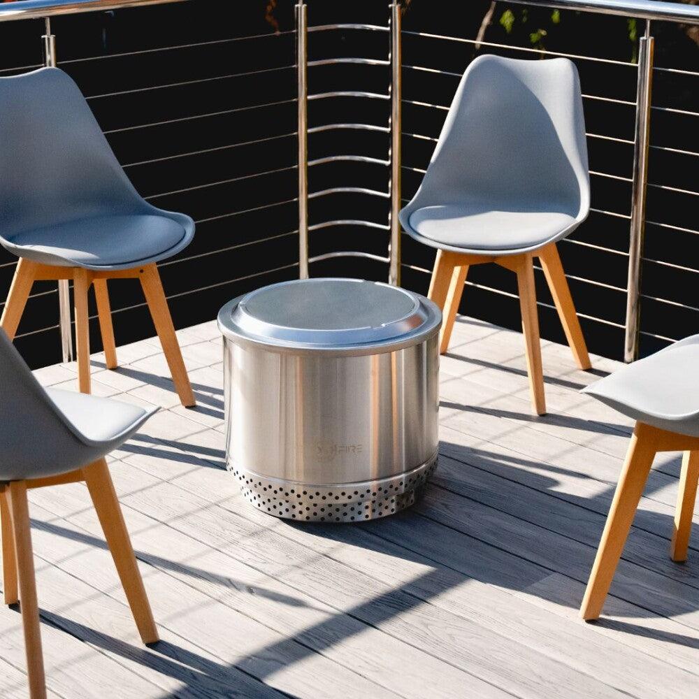 Stainless steel fire pit on a wooden deck with chairs around it