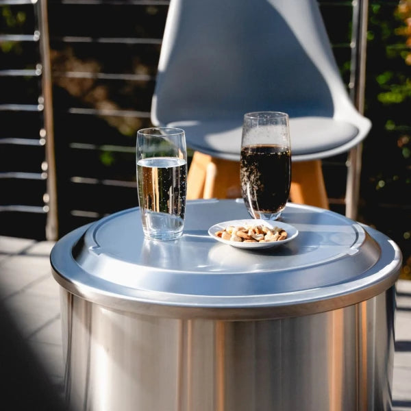 Two glasses of drinks on a metal table outdoors with a chair in the background.