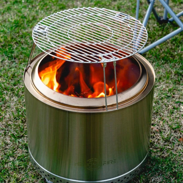 Portable camping stove with grill on a grassy background