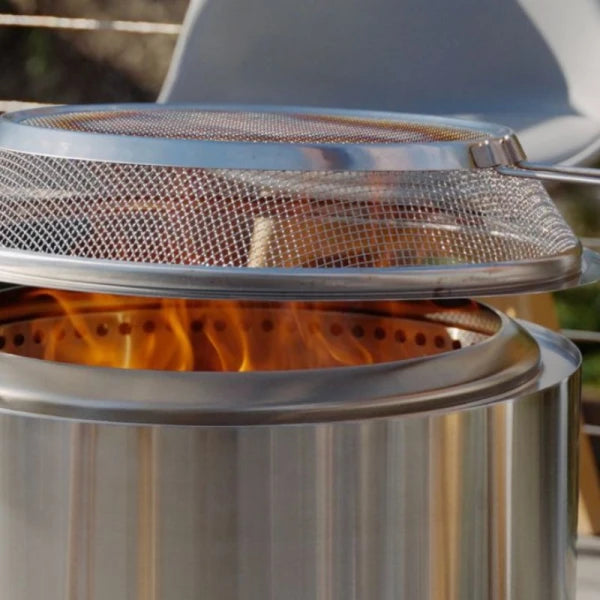 Metal fire pit with mesh cover on flames