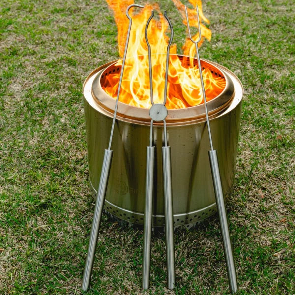 Metal fire tongs over a campfire on grass