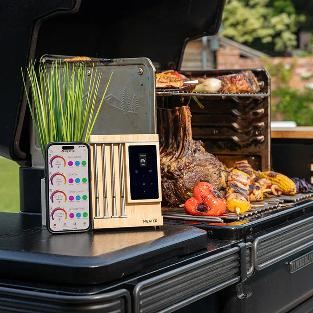 Meater digital meat thermometer on a grill with food and smartphone