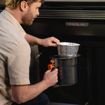Person using a portable grill with a TIMBERLINE logo in the background